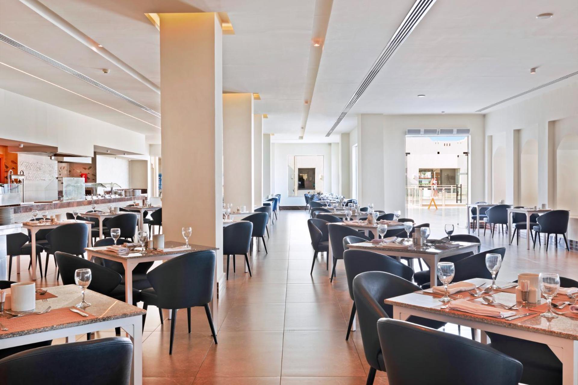 Pickalbatros Royal Grand Sharm - Adults Friendly 16 Years Plus Exterior photo The photo shows the interior of a modern restaurant. The space is bright and airy, featuring large windows that allow natural light to flood in. There are several tables arranged throughout the room, each covered with placemats and set with glasses a