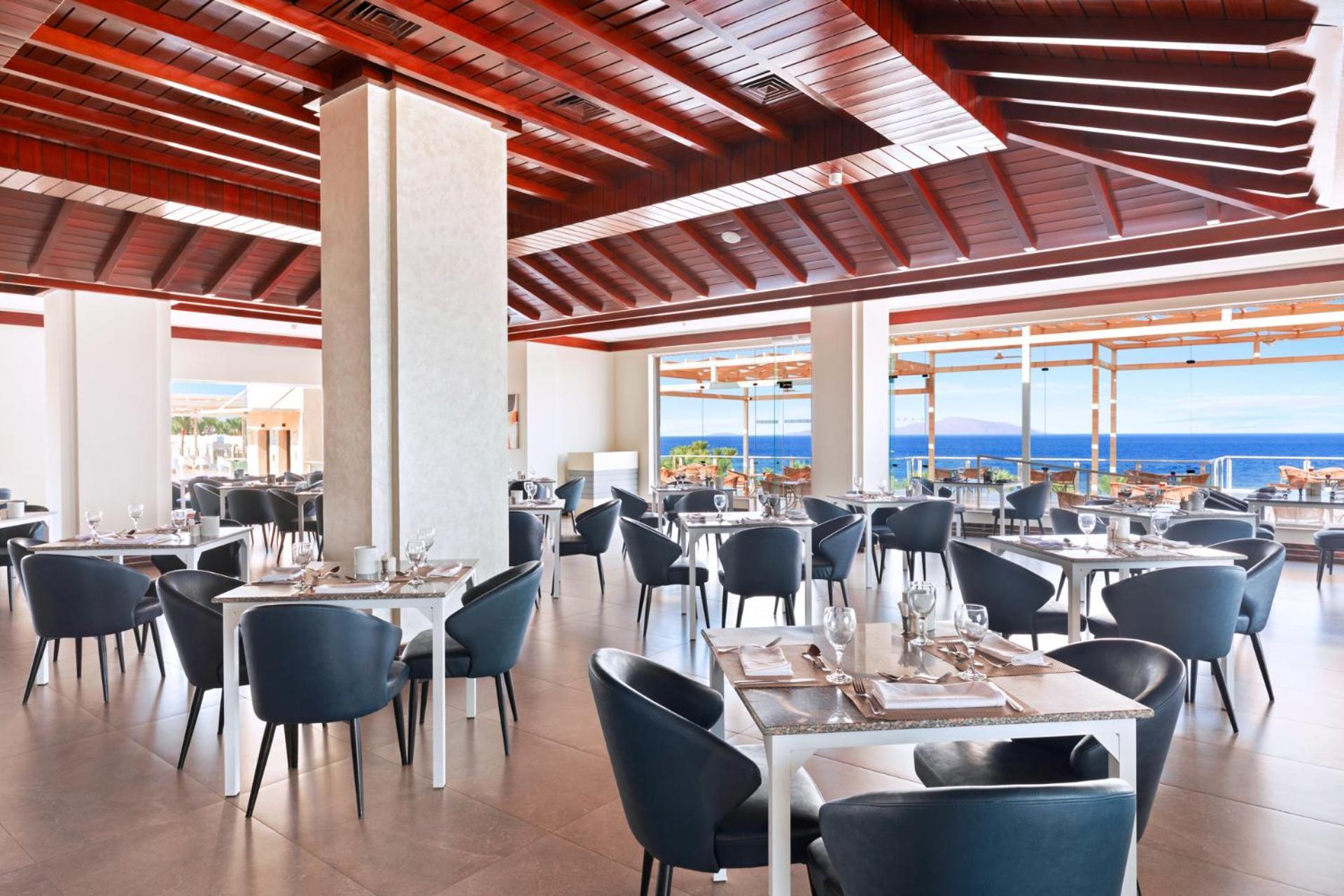 Pickalbatros Royal Grand Sharm - Adults Friendly 16 Years Plus Exterior photo The photo shows a modern restaurant interior with a spacious and well-lit design. There are several tables set for dining, featuring white tablecloths and elegant dinnerware. The chairs are sleek and dark, contrasting with the bright surroundings. La