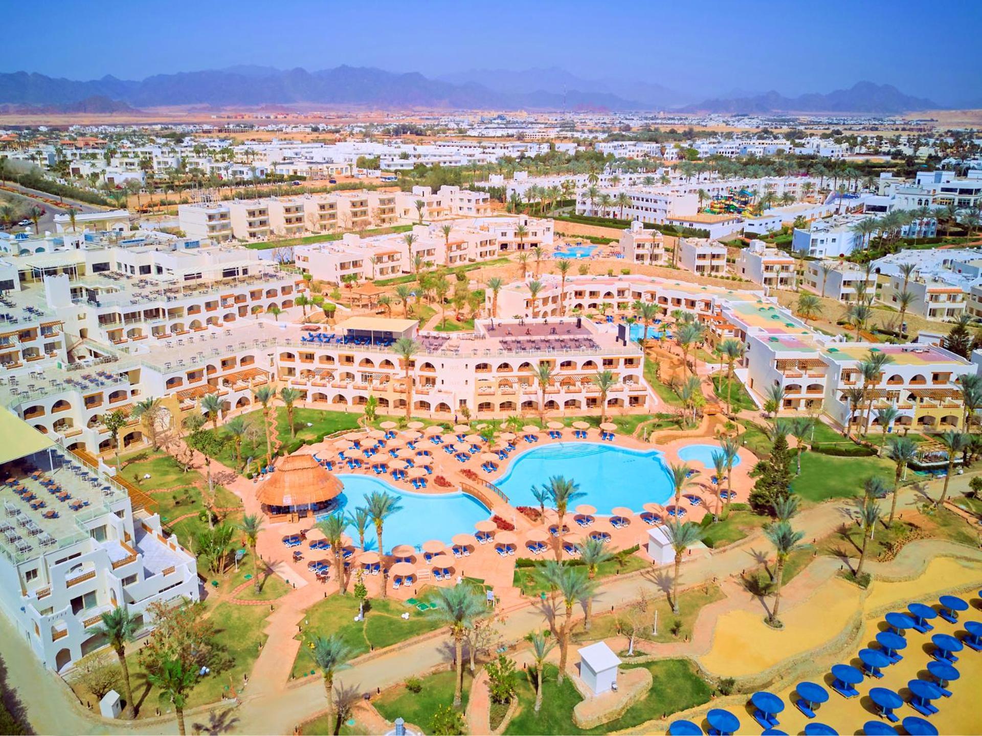 Pickalbatros Royal Grand Sharm - Adults Friendly 16 Years Plus Exterior photo The photo shows an aerial view of a resort complex. There are several buildings arranged around a central area that features swimming pools. The pools are surrounded by palm trees and lounge chairs, indicating a tropical or sunny climate. In the back