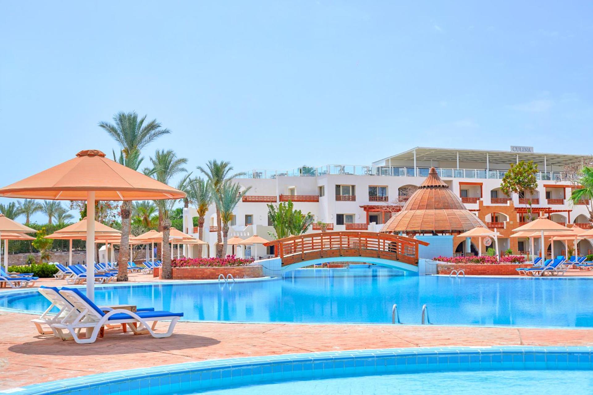 Pickalbatros Royal Grand Sharm - Adults Friendly 16 Years Plus Exterior photo The photo depicts a beautiful resort setting featuring a large, inviting swimming pool. There are several lounge chairs positioned around the pool, along with straw umbrellas providing shade. In the background, there is a charming wooden bridge archi