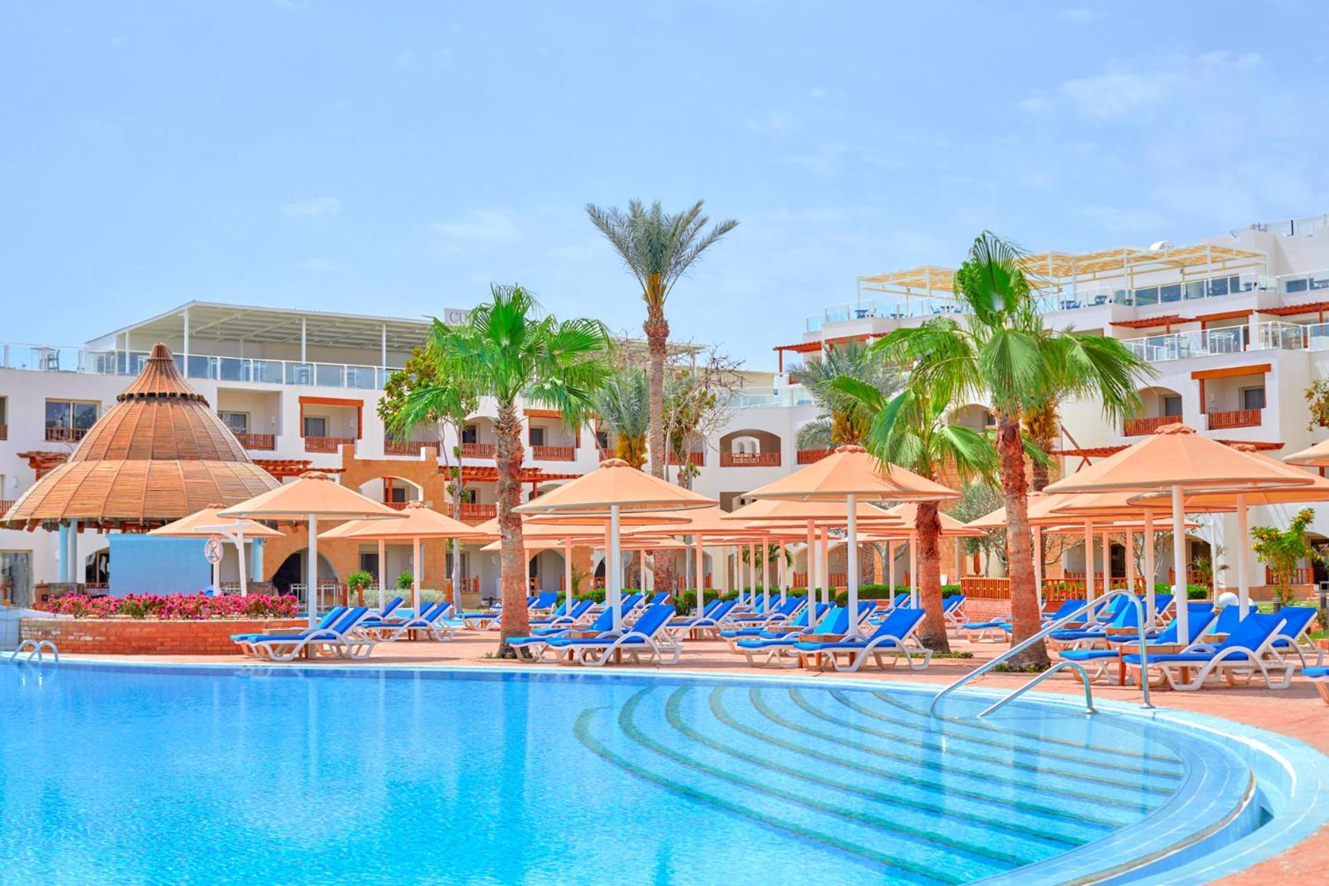 Pickalbatros Royal Grand Sharm - Adults Friendly 16 Years Plus Exterior photo The photo depicts a resort scene featuring a beautiful swimming pool with clear blue water. Surrounding the pool are several lounge chairs arranged under large umbrellas, providing shade. In the background, there are palm trees that enhance the tropi